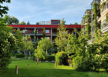 Das Bild zeigt eine Parkanlage, Fassadenbegrünung und Dachgarten in der Wohnanlage Wagnis 4 in München