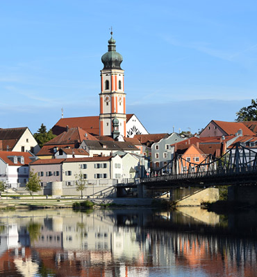 Das Foto zeigt einen Ort mit Kirche, Fluss und Brücke.