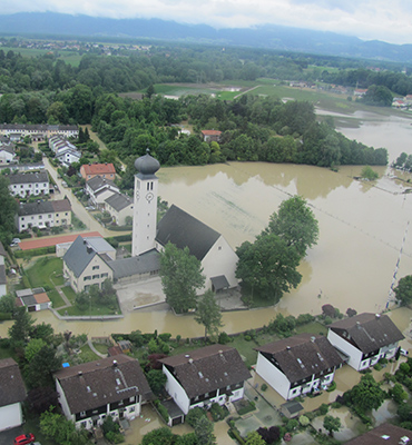Das Bild zeigt eine beim Hochwasser 2013 überschwemmte Siedlung mit einer im Wasser stehenden Kirche und Wohngebäuden